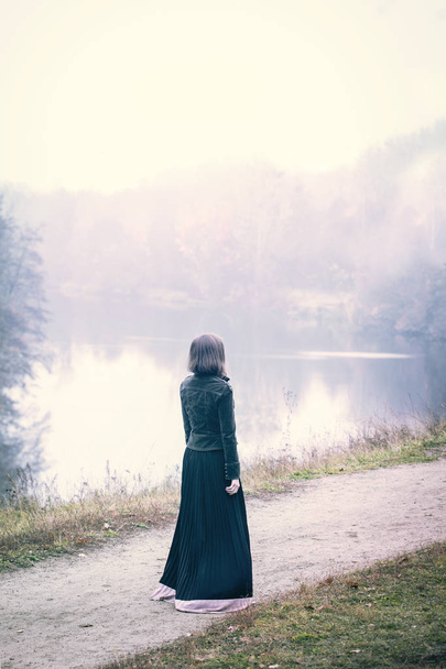 Vrouw in oude kleren wandelen in mistig weer - Foto, afbeelding
