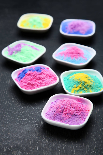 Colorful holi powder in bowls on black wooden table - Фото, зображення