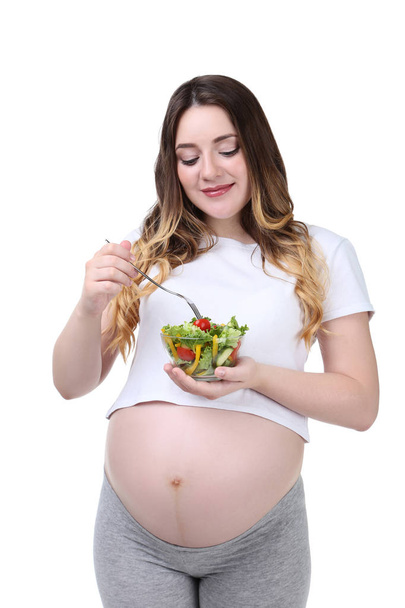 Beautiful pregnant woman with fresh salad in bowl on white background - Фото, зображення