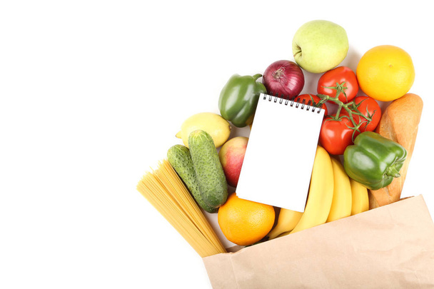 Grocery shopping bag with food and blank notepad on white background - Foto, afbeelding