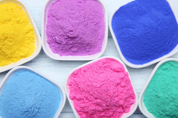 Colorful holi powder in bowls on wooden table - Фото, зображення