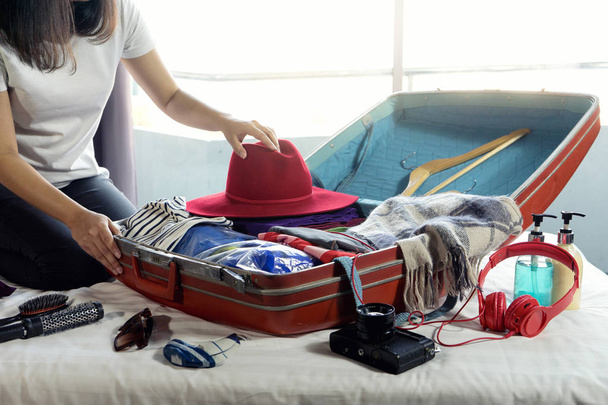 Mädchen packt das Gepäck und bereitet sich mit viel Stoff auf die Reise vor - Foto, Bild