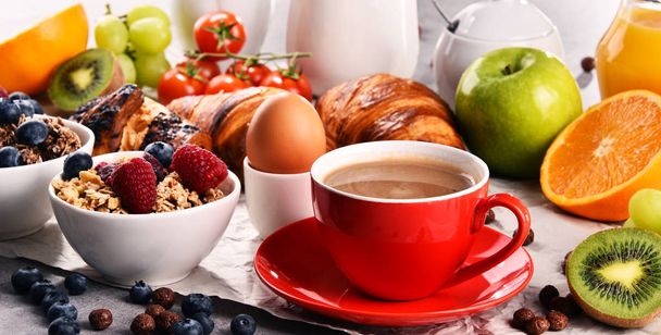 Śniadanie serwowane z kawą, sokiem pomarańczowym, rogalikami, jajkiem, płatkami zbożowymi i owocami. Zrównoważona dieta. - Zdjęcie, obraz