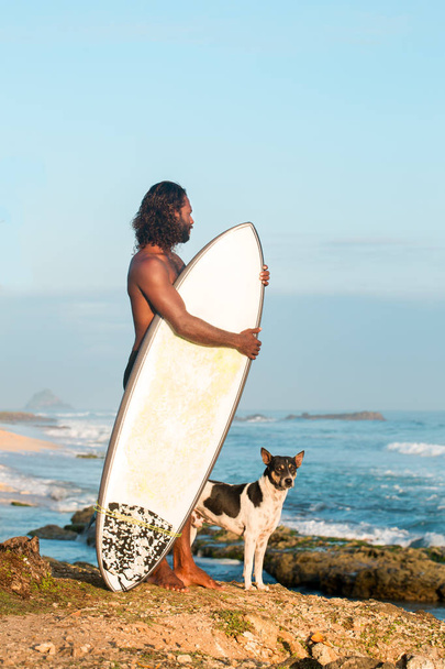 Surffaaja pitää surffilautaa Intian valtameren rannalla.
 - Valokuva, kuva