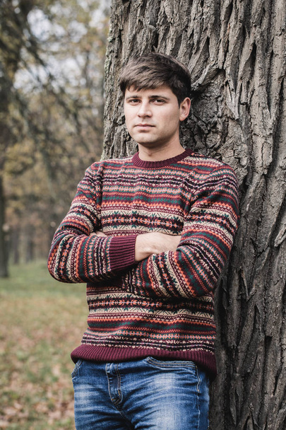 Przystojny, młody człowiek w sweter z dzianiny w jesienny park - Zdjęcie, obraz