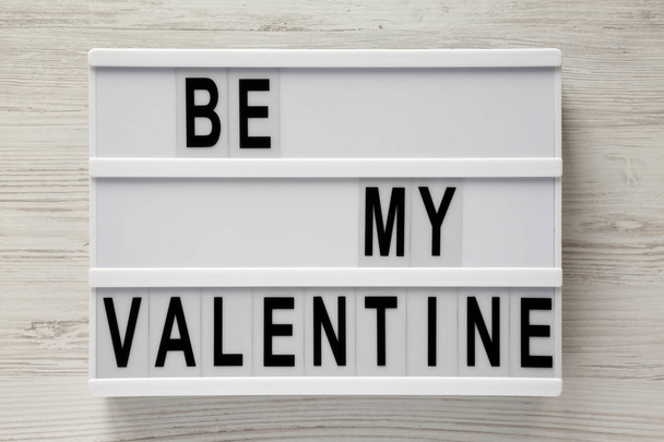 Современная доска с текстом "Будь моим Валентином" на белом деревянном столе. День святого Валентина 14 февраля
. - Фото, изображение