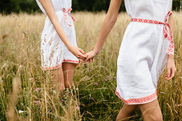 partial view of women in ethnic clothes holding hands in summer field - Foto, imagen