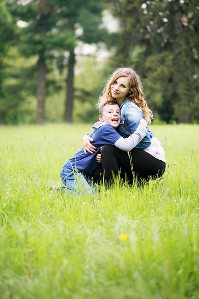 若い母親が牧草地で彼女の息子と遊ぶ - 写真・画像