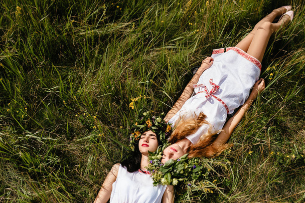 overhead view of young beautiful women in ethnic clothes resting on green grass - Foto, Imagem