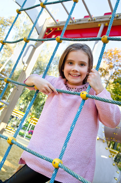 Onnellinen hymyilevä cutu pieni tyttö lapsi leikkipaikka laitteet ulkona
 - Valokuva, kuva