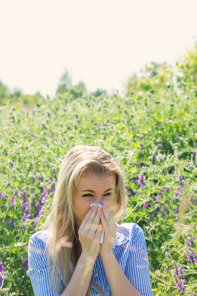 Blonde woman suffering from seasonal allergies in the meadow - Photo, Image