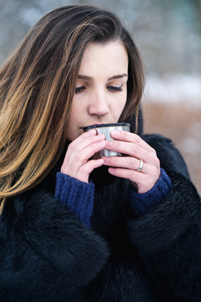 Una mujer está tomando una bebida caliente en el frío
 - Foto, Imagen
