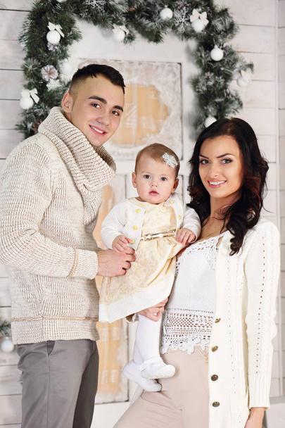Familia feliz, padre, madre e hija en el porche con decoraciones navideñas
 - Foto, Imagen