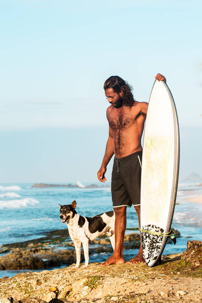 De surfer is het houden van een surfplank aan de kust van de Indische Oceaan - Foto, afbeelding