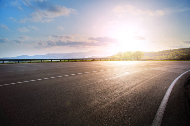 Leere asphaltierte Autobahnkurve und Sonnenuntergang - Foto, Bild