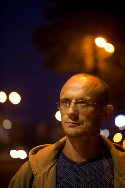 Un joven con gafas en el fondo de las luces de la ciudad nocturna
 - Foto, Imagen