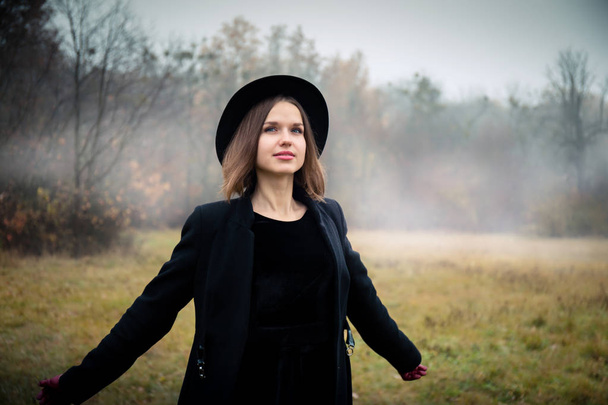 Жінка в чорному пальто і капелюсі в туманній погоді
 - Фото, зображення
