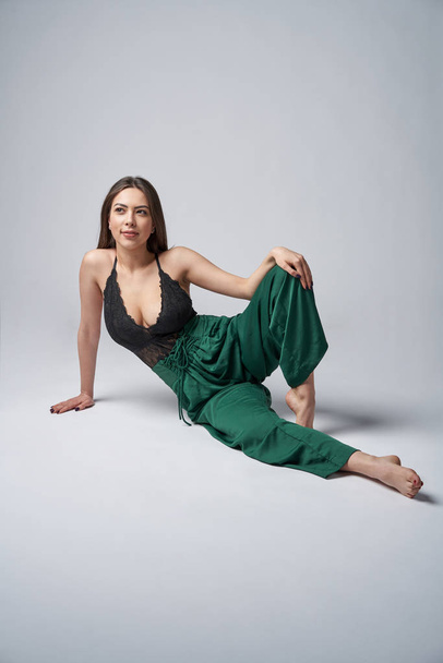 Sensual brunette female in green trousers and top with deep cleavage - Fotoğraf, Görsel