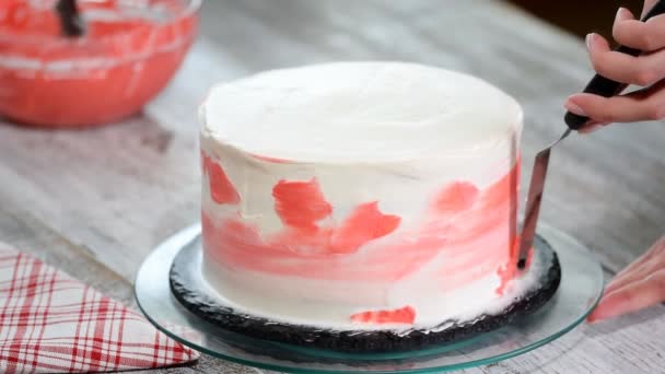 Кондитерская рука мажет розовый крем на белом глазури крем торт на деревянном проигрывателе в пекарне кухни, закрыть
 - Кадры, видео