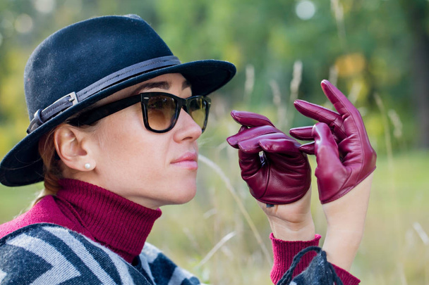 schöne Frau mit Poncho-Mütze und Handschuhen spaziert durch den Park - Foto, Bild