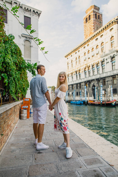 Young beautiful couple girl in dress man in white shirt walk through the streets of Venice Italy - Foto, imagen