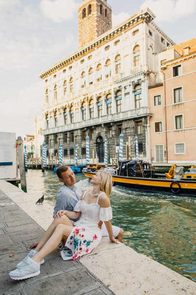 Young beautiful couple girl in dress man in white shirt walk through the streets of Venice Italy - Фото, изображение