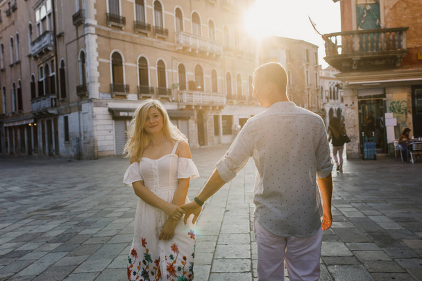 Young beautiful couple girl in dress man in white shirt walk through the streets of Venice Italy - Fotoğraf, Görsel