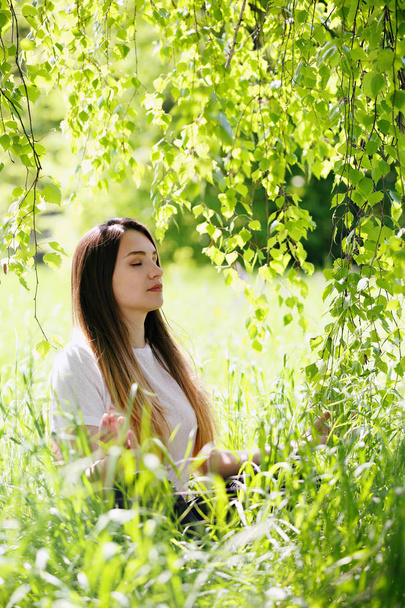 woman meditating in the lotus position in the shade of a tree - Photo, Image
