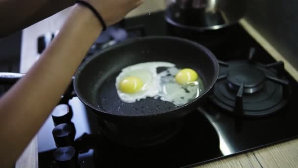 A woman cracks a fresh eggs in a frying pan with hot, sizzling butter. Late breakfast after shower - Záběry, video