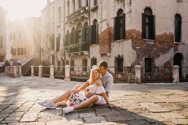 Young beautiful couple girl in dress man in white shirt walk through the streets of Venice Italy - 写真・画像