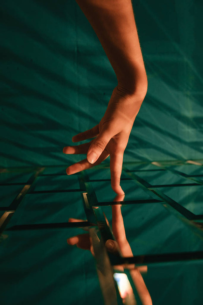Γυναικείο χέρι αγγίζει στυλιζαρισμένη σχεδιαστής τούβλο γυάλινο τοίχο - Φωτογραφία, εικόνα