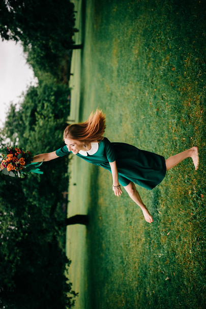 fiatal vörös hajú nő zöld ruhában, nyári virágok csokor - Fotó, kép
