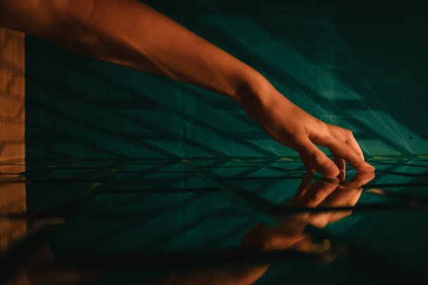 A woman's hand touching a stylized designer green brick glass wall - Φωτογραφία, εικόνα