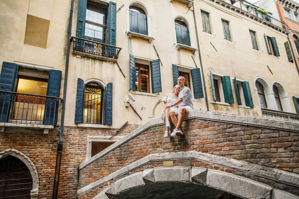 Young beautiful couple girl in dress man in white shirt walk through the streets of Venice Italy - Fotoğraf, Görsel