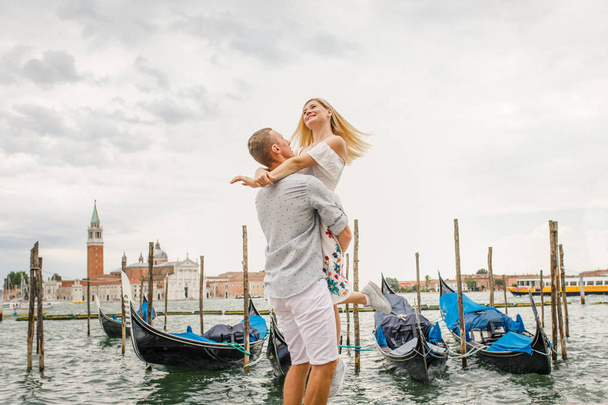 Young beautiful couple girl in a white dress a man in a white shirt walk near the water overlooking the Grand Canal in Venice Italy - Foto, imagen