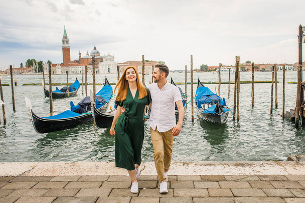 Young beautiful couple girl in a green dress a man in a white shirt walk near the water overlooking the Grand Canal in Venice Italy - Foto, afbeelding