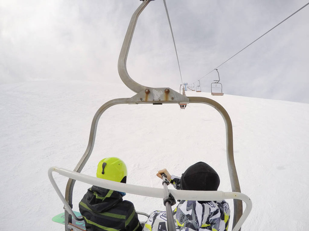 Meisje op een snowboard en een jongen op ski's in de bergen. Veel sneeuw. Karpaten. Ski-jas en broek. Paar op actieve winter rest - Foto, afbeelding