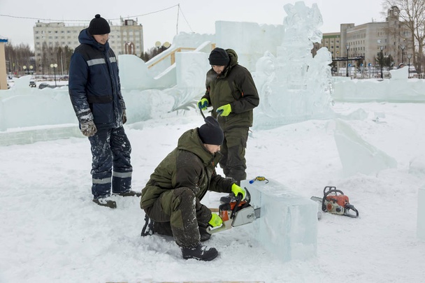 Trabajador sierra una placa de hielo de motosierra en una ciudad de hielo
 - Foto, Imagen