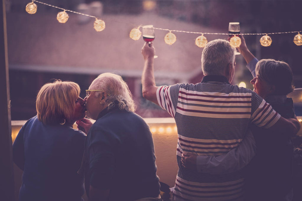 twee senior paar samen vieren op terras met stad bekijken  - Foto, afbeelding