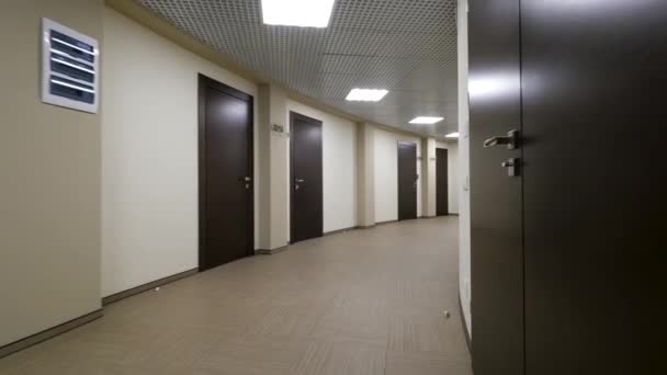 Άδειο, στρογγυλή διάδρομος με ανοιχτό μπεζ τοίχους και κεκλεισμένων, σκούρο καφέ. Κλειστές πόρτες κατά μήκος ένα φωτιζόμενο διάδρομος για το κτίριο γραφείων. - Πλάνα, βίντεο