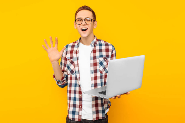 the man in glasses with a laptop, on a yellow background, man doing online purchases - Fotografie, Obrázek