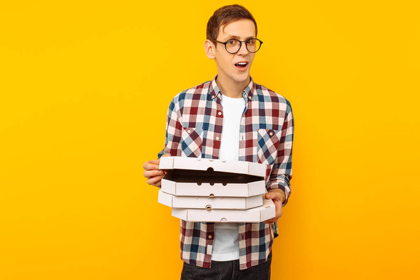 man holding a box of pizza on a yellow background, a happy man with a pizza in his hands - Photo, Image