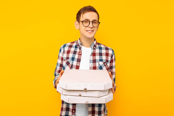 pizza sarı bir arka plan üzerinde onun elinde bir pizza ile mutlu bir adam bir kutu tutan adam - Fotoğraf, Görsel