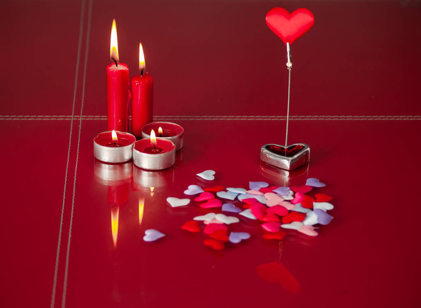 Concept of love Red candles lit and a lot of hearts with a red background - Photo, Image