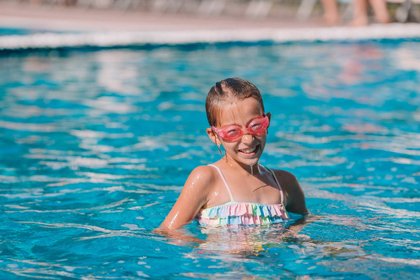 Красивая маленькая девочка развлекается у открытого бассейна
 - Фото, изображение