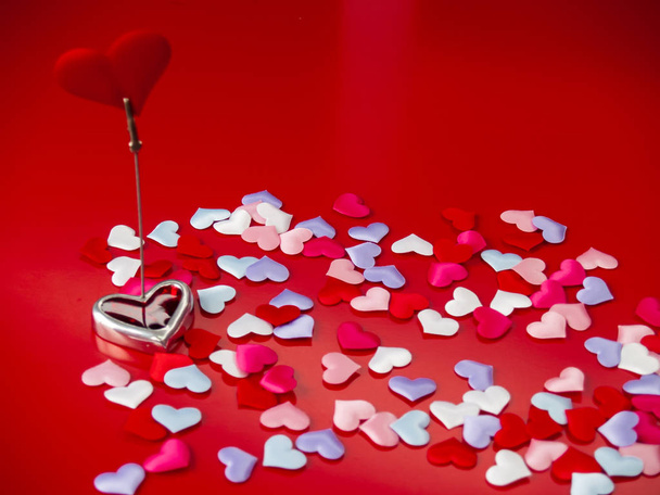 Concepto de amor Un stand con un corazón rojo y fondo rojo con un montón de pequeños corazones multicolores
 - Foto, imagen