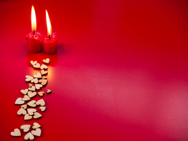 Rakkauden käsite Punainen kynttilä palaa ja paljon puisia sydämiä punaisella taustalla
 - Valokuva, kuva