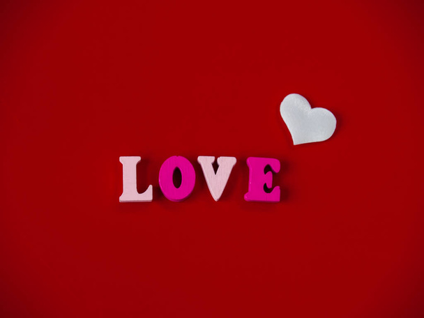 Concept of love The word love in wooden letters and hearts with a red background - Photo, Image