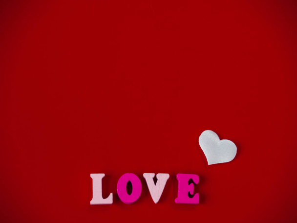 Έννοια της αγάπης, η λέξη αγάπη στα ξύλινα γράμματα και τις καρδιές με κόκκινο φόντο - Φωτογραφία, εικόνα