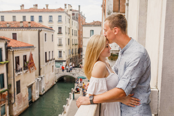 Joven hermosa pareja está de pie en el balcón con vistas a la hermosa Venecia
 - Foto, imagen